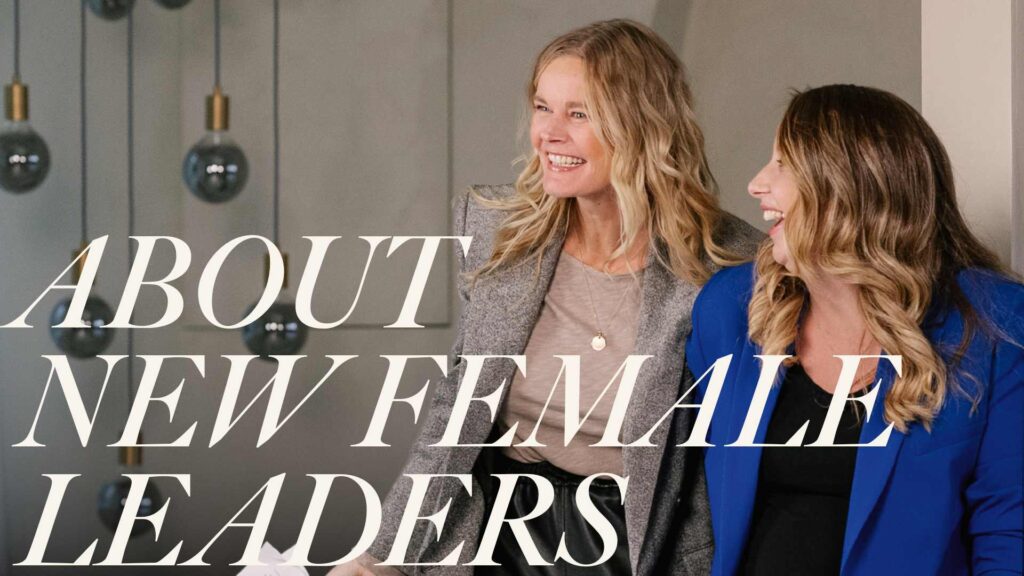 Twee lachende vrouwen in professionele kleding staan samen voor een achtergrond met hangende lampen, met de tekst "About New Female Leaders" over de afbeelding.