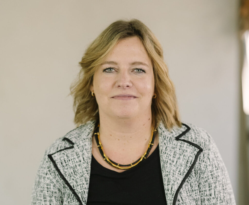 Portret van een vrouw die symbool staat voor nieuw leiderschap, gekleed in een zwart-witte blazer en zwarte top.