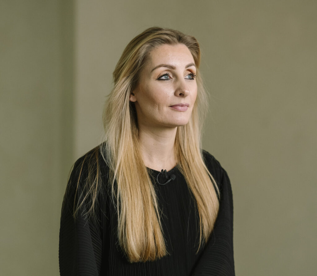 Portret van een zelfverzekerde vrouwelijk leider met lang blond haar in een zwarte outfit.