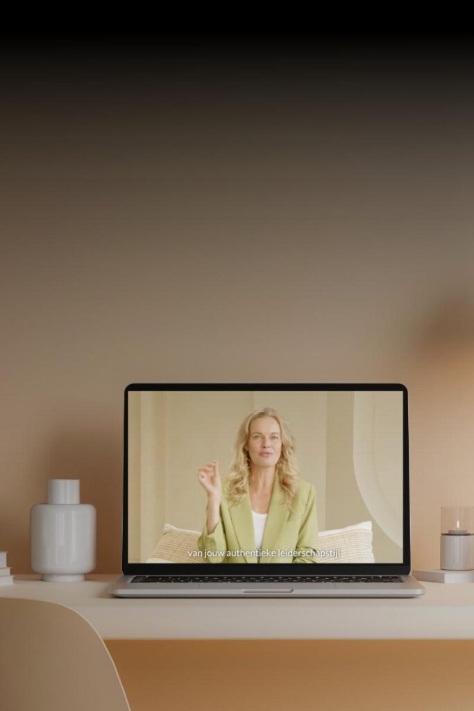 Laptop op een bureau met een video over online leren in leiderschap waarin een vrouw spreekt.