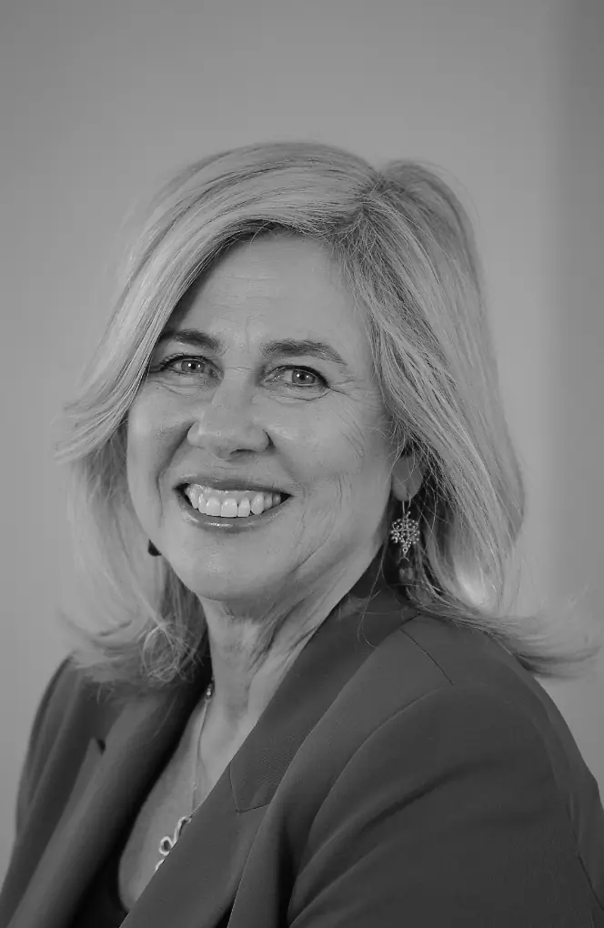 Portretfoto van coach Caroline van den Boogaard met een glimlach, in zwart-wit.