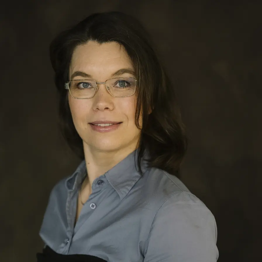 Portret van een vrouw met bril en donker haar, geassocieerd met het New Female Leader Instituut.