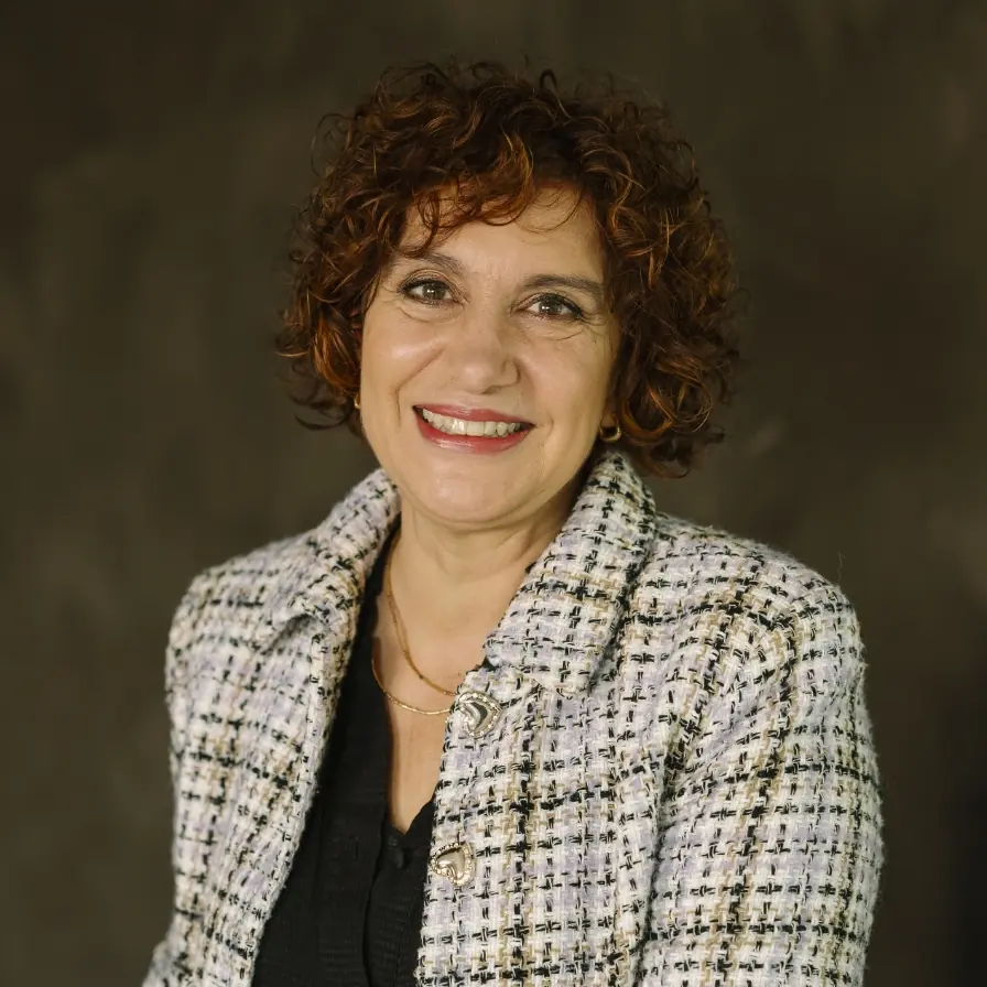 Vrouwelijke deelnemer van het New Female Leader-leiderschapsprogramma poseert glimlachend voor een neutrale achtergrond.