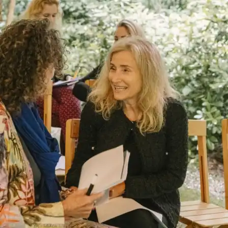 Twee vrouwen in gesprek tijdens het New Female Leaders Festival in een groene, informele setting.