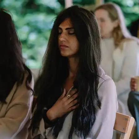 Vrouw met gesloten ogen legt hand op haar borst tijdens een rustmoment op het New Female Leaders Festival – House of NFL.