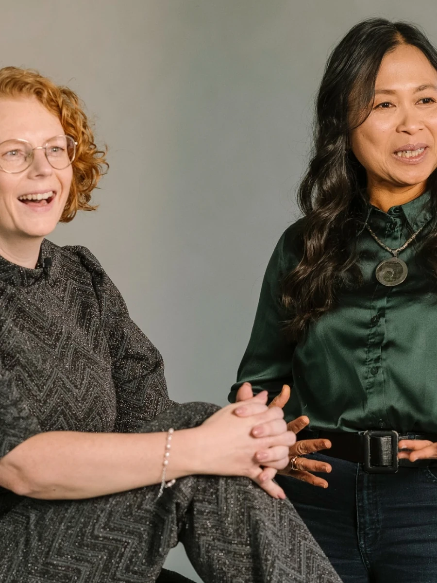 Twee vrouwen van het programma The Accelerator lachen en praten tijdens een fotoshoot.